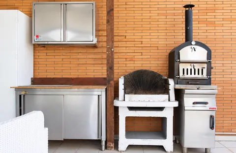 La cuisine extérieure sous la véranda, avec barbecue et four