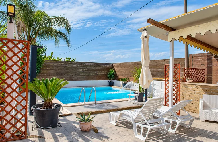La piscine avec la pergola, le parasol et les transats