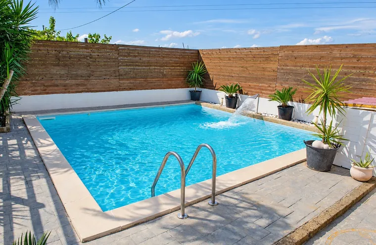 La piscine avec son échelle et les plantes en pot